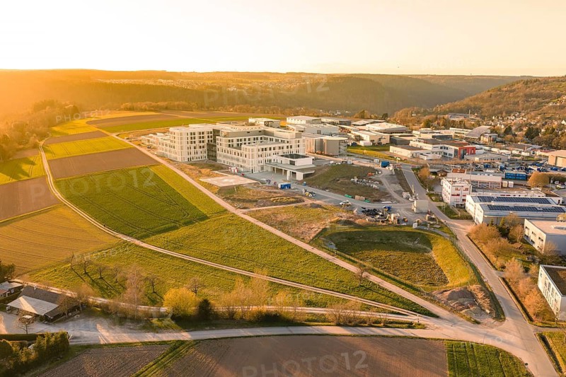 Wide aerial view of a landscape scene with buildings and green fields in the evening light, new hospital at the Verbund Südwest Clinic, Calw, Germany