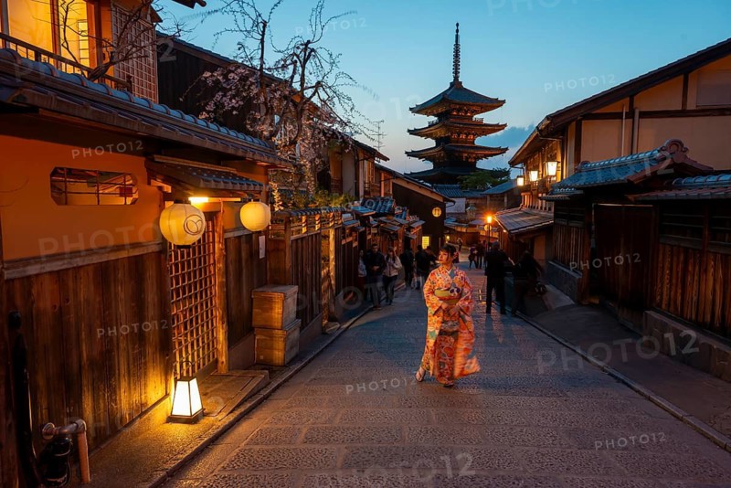 Japanese woman in kimono in an alley, Yasaka dori historic alleyway in the old town with traditional Japanese houses, five-story Yasaka Pagoda of the Buddhist Hokanji Temple in the back, evening mood, blue hour, Higashiyama, Kyoto, Japan