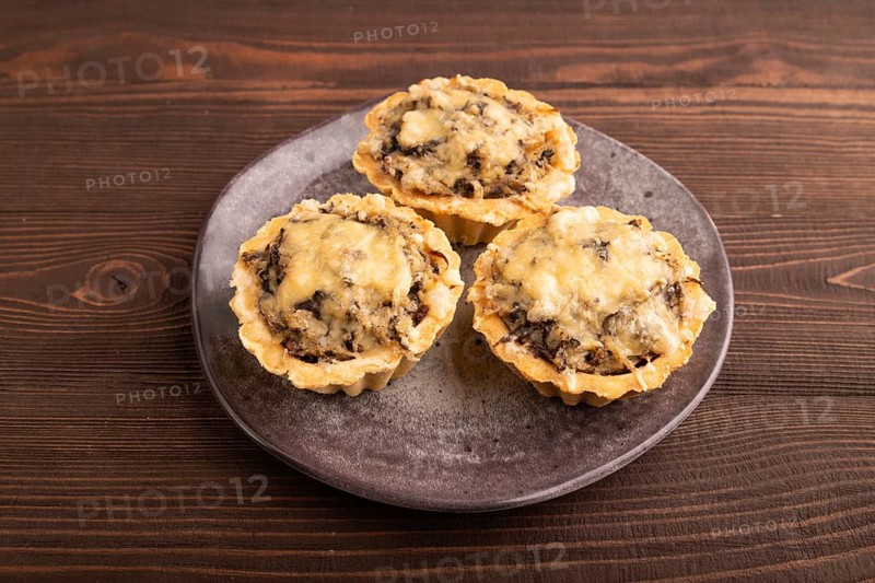 Tartlets with meat and cheese on brown wooden background. side view, close up