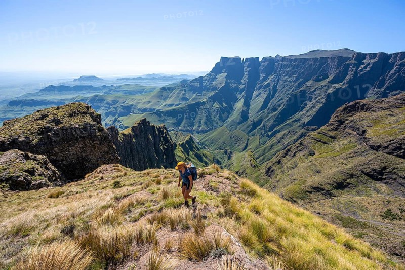 Young hiker looking at the impressive mountains and cliffs of the Drakensberg Mountains, hiking trail on the Sentinel Hiking Trail, Drakensberg, KwaZulu-Natal, South Africa