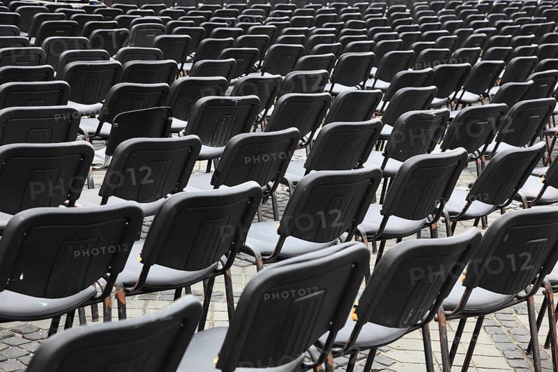 Chairs covered with gray plastic stand in rows in a function room, empty, vacant, seating