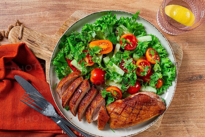 Delicious grilled duck breast served with fresh garden salad and cherry tomatoes at a rustic dining table
