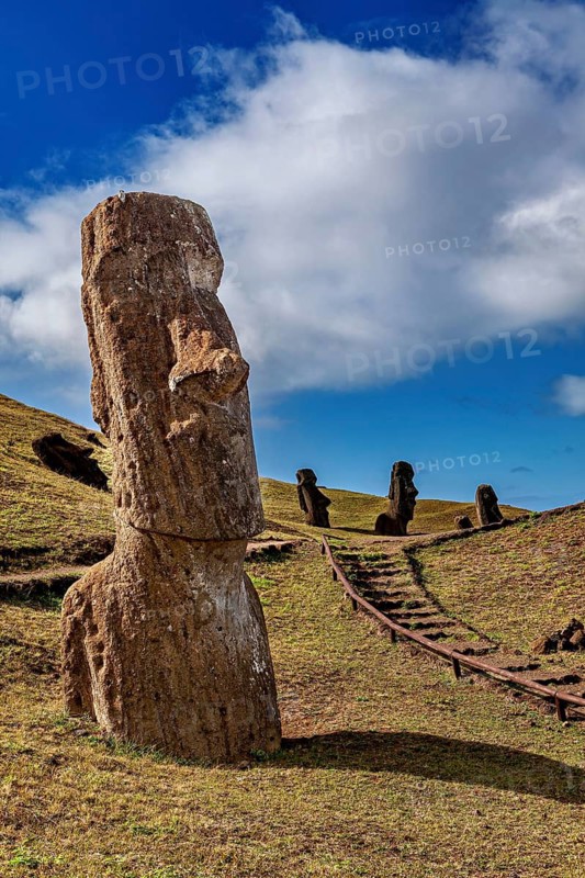 A single moai in the foreground with other statues in the background on a hill, The moai statues on Easter Island in the Pacific Ocean