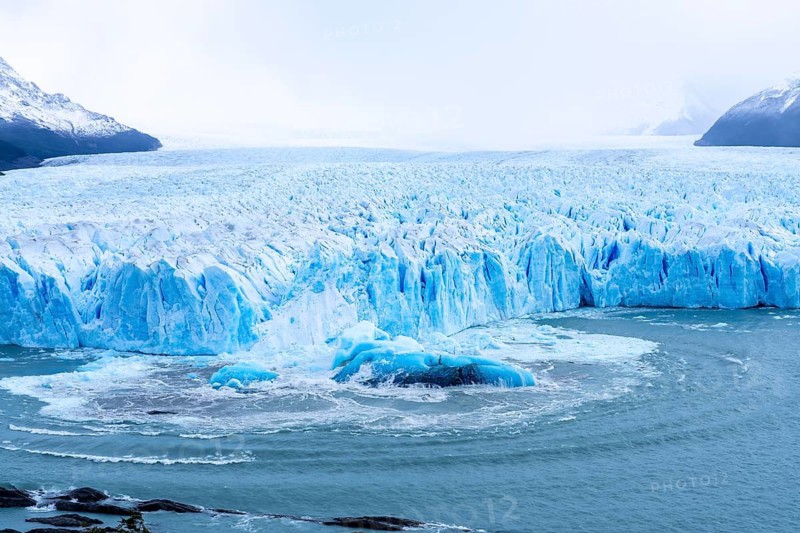 Perito Moreno glacier, calving front with blue glacial ice and turbulent water following an ice break in Lake Argentino, snow-capped mountains in the background, Los Glaciares National Park, Santa Cruz province, Patagonia, Argentina