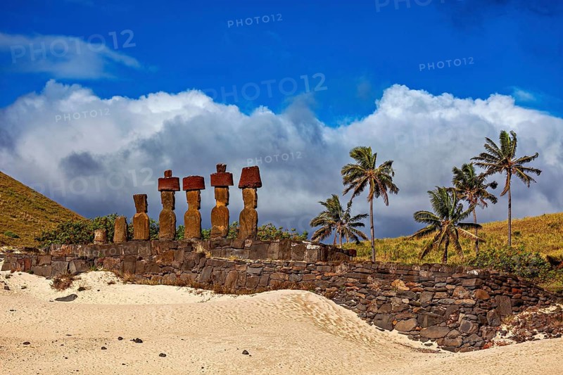 Historic image of stone statues and palm trees, with clouds and blue sky on Easter Island, The Moai statues on Easter Island in the Pacific Ocean