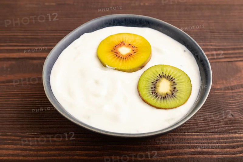 Yogurt, with kiwi in blue bowl on brown wooden background, side view, close up, minimalism