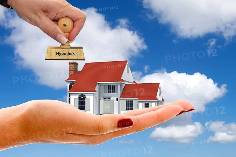 Hand with single-family house, cumulus clouds, blue sky, spring in northern Germany, dream home, construction financing, credit, stamp, mortgage, studio shot, Federal Republic of Germany