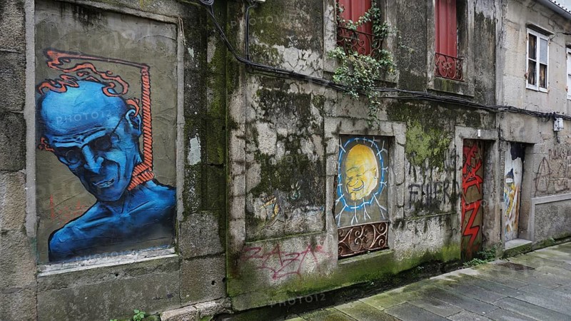 Graffiti on old buildings in an urban environment with blue and colorful elements, hiking on the Caminho Portugues da Costa, Portugal
