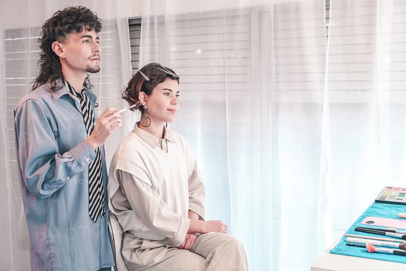 Professional makeup artist applying makeup on a model's face in a bright, airy beauty salon, highlighting diversity and inclusion in the beauty industry