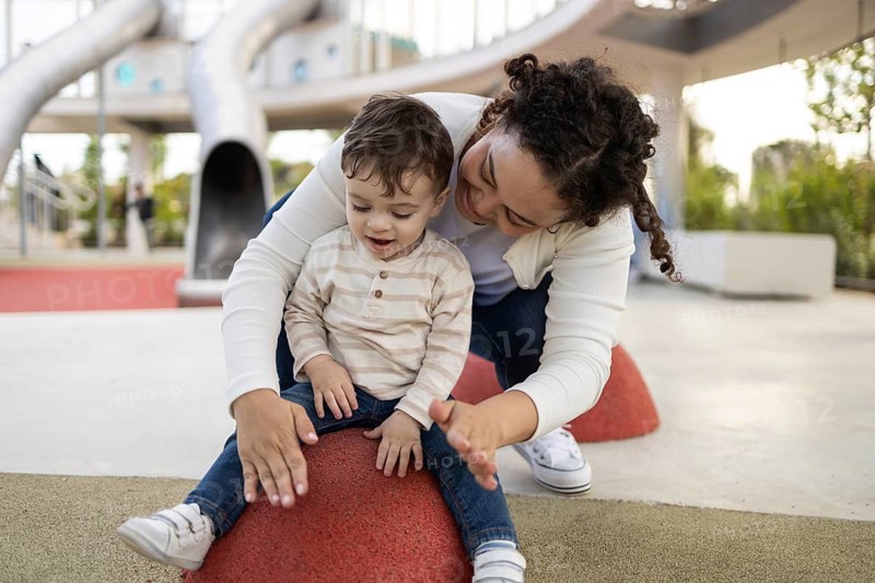 A joyful moment in the park as a mother and her baby engage in play. The scene captures a warm bond, highlighting the joy of outdoor family activities on a sunny day