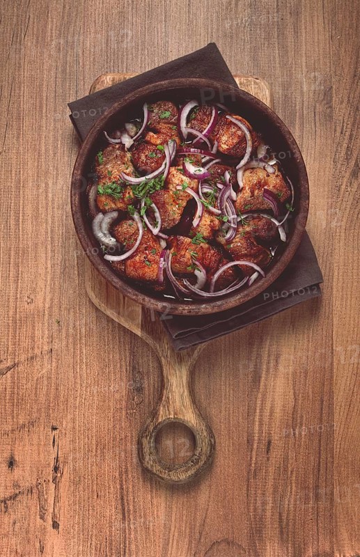 Fried meat, pork kebab, ketsi in a clay pan, with red onions and herbs, homemade, no people