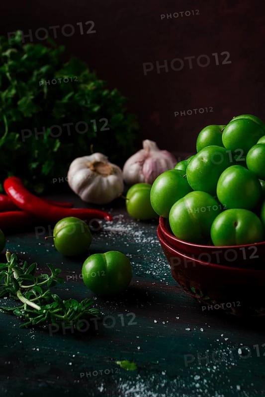 Tkemali, green cherry plum, with ingredients for sauce, cilantro, mint, hot pepper, garlic, on a wooden table, close-up, rustic, food background, no people, selective focus