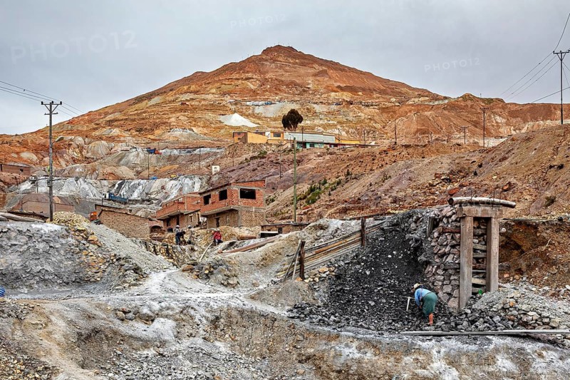 Small buildings on a mountainside with active mining operations and grey skies, The silver mines of Potosi on Cerro Rico in Bolivia