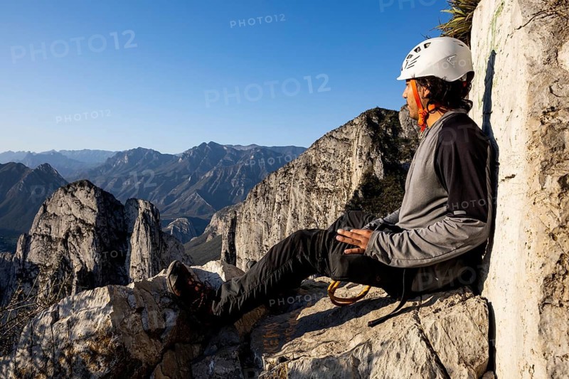 A mountaineer takes a break while practicing climbing and rappelling at Eagleâ€™s Nest in Monterrey, Mexico. The scenic rock face and clear blue sky create a stunning outdoor setting