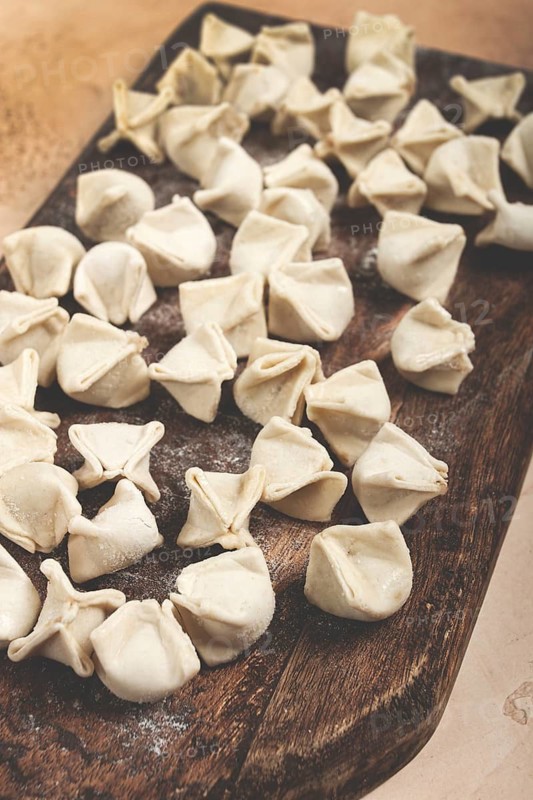 Traditional Turkish dumplings, raw, on a cutting board, top view, no people