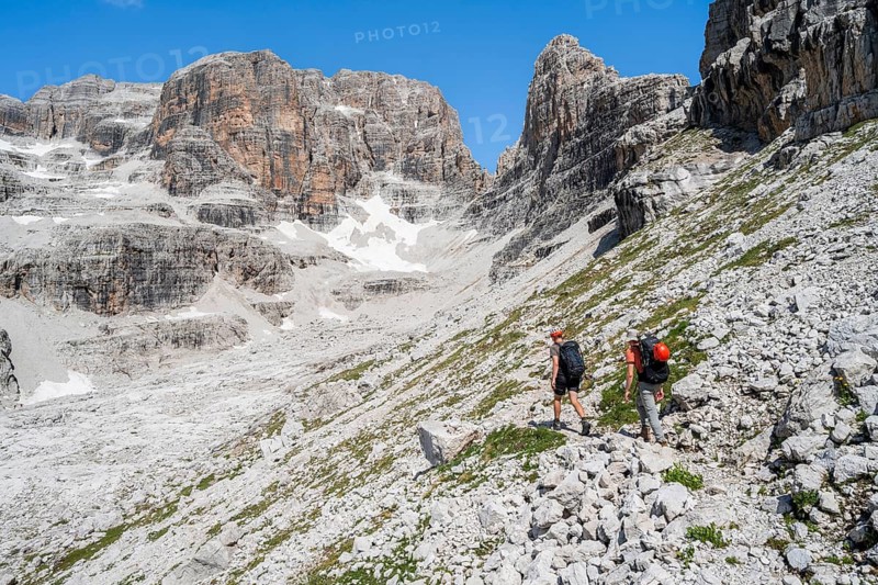Two mountaineers on a hiking trail to Sella della Tosa, mountainous landscape in the Brenta Mountains, Brenta-Adamello Natural Park, Trentino, Italy