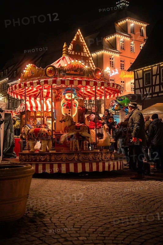 Evening scene with illuminated carousel and people at a Christmas market, Christmas market Calw, Black Forest, Germany