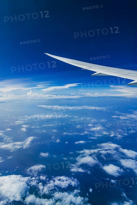 View from the aircraft window during a flight over India with the airline Etihad. Blue sky and cloud structures over the sea, wing of a Boeing 787 aircraft