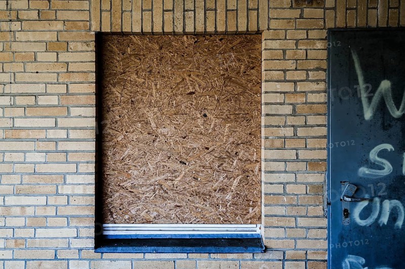 Old building with brick walls and a window covered with OSB panels