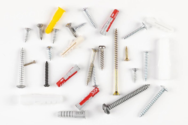 Various screws and plugs scattered on a white surface