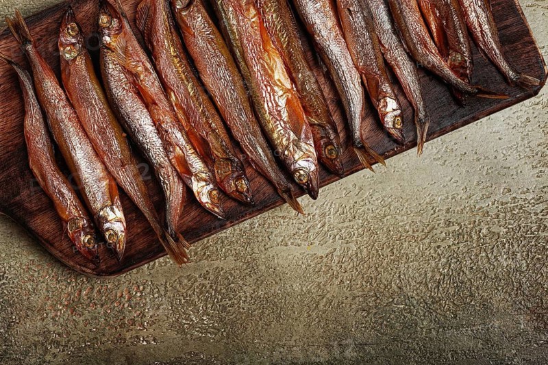Cold smoked capelin, on a wooden chopping board, no people