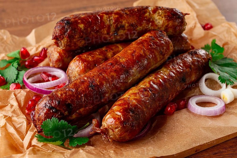 Fried kupaty on parchment, with red onion and pomegranate, kupaty, Georgian cuisine