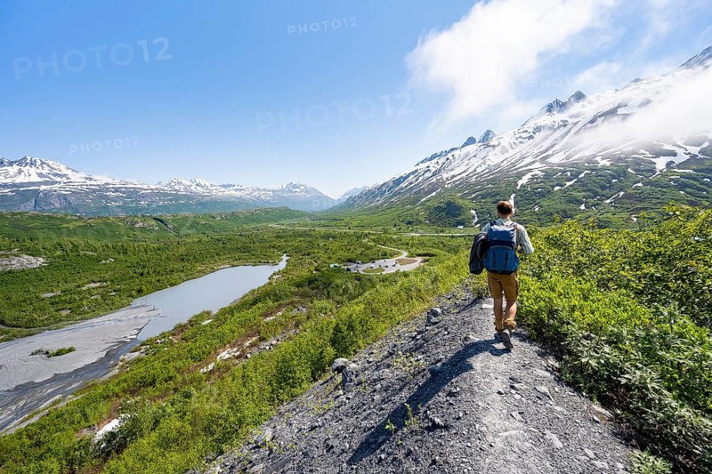 Hikers on glacial moraine, view of the vast Tsina River valley with mountains, Worthington Glacier Lagoon, Worthington Glacier State Recreational Site, Chugach Mountains, Alaska, USA