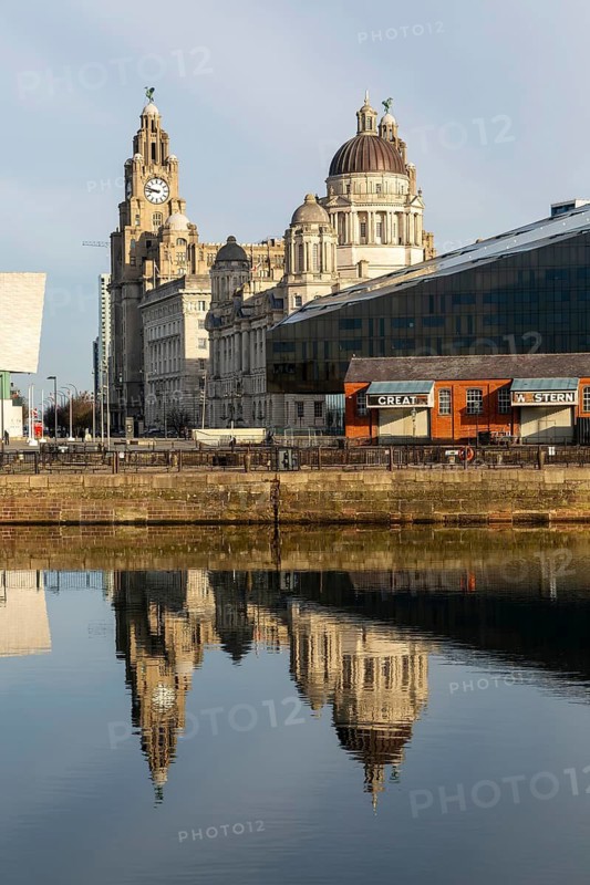 The Three Graces iconic waterfront landmark buildings reflected in water, Canning Dock, Liverpool, England, UK