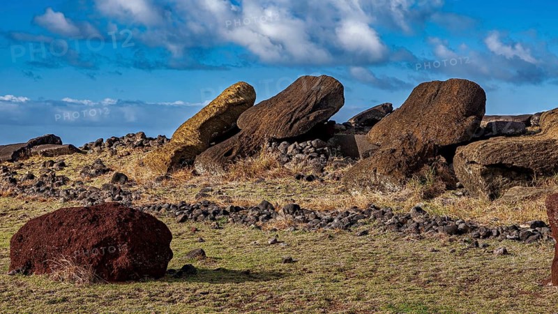 Three fallen moai lie side by side under a cloudy sky on Easter Island, the moai statues on Easter Island in the Pacific Ocean