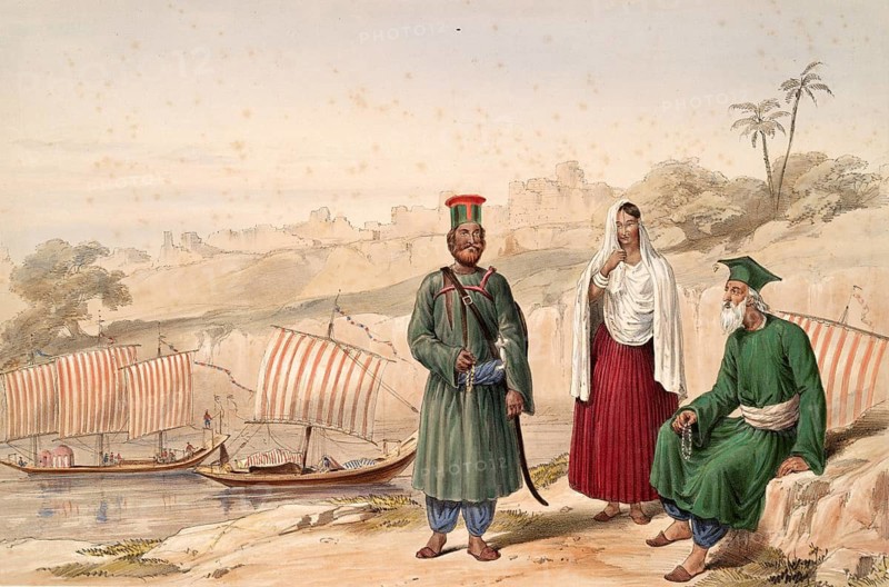 Three people in historic clothing with a river and sailboats in the background on a shore