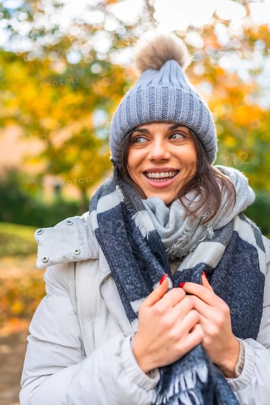 Vertical photo of a caucasian cute beauty woman with warm clothes in a park during autumn