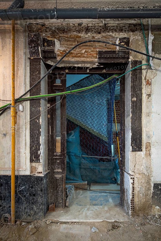 A historic building entrance under renovation, showing exposed bricks, wires, and scaffolding. A glimpse into the careful process of architectural restoration