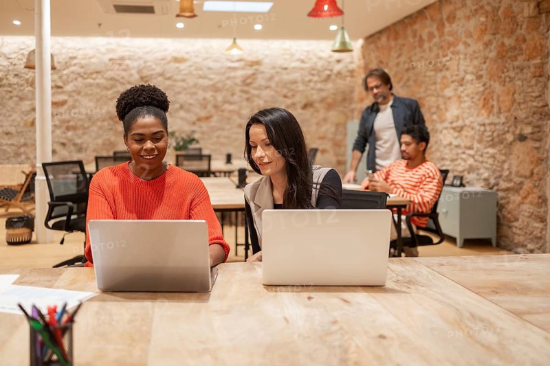 A vibrant coworking space with professionals engaged at laptops, fostering creativity and collaboration The cozy brick interior enhances the modern workspace ambiance