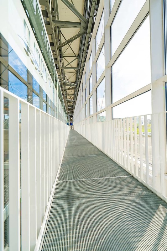 Long, light-flooded corridor with metal floor and glass windows, Motorworld Böblingen, Germany