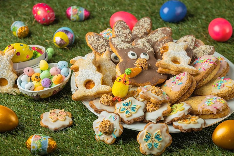 Decorated Easter cookies on a plate with colorful eggs in the grass