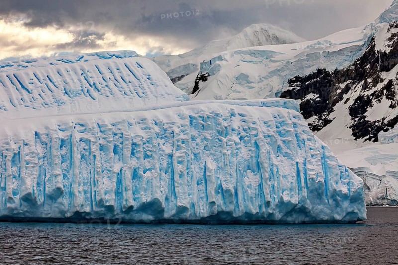 Single massive iceberg against a dark, cloudy backdrop, icebergs in the Southern Ocean in Antarctica