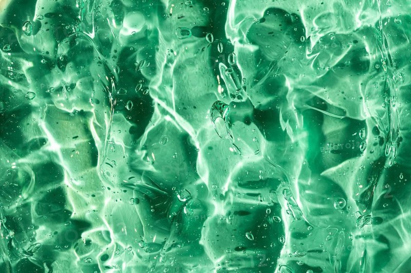 Close-up of a vibrant green gel texture, highlighting its translucent quality and intricate light reflections. Perfect for backgrounds or abstract compositions
