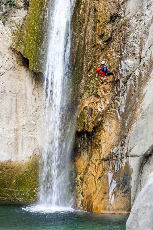 A canyoneer rappels down steep cliffs next to a waterfall, surrounded by breathtaking natural beauty, in Matacanes, Nuevo Leon, Mexico