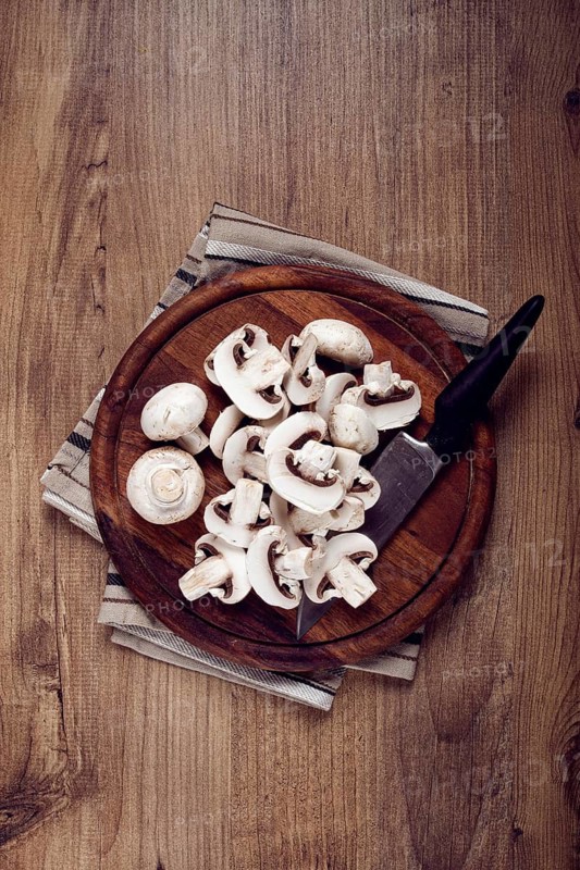 Fresh mushrooms, chopped, in a wooden bowl, whole, top view, no people