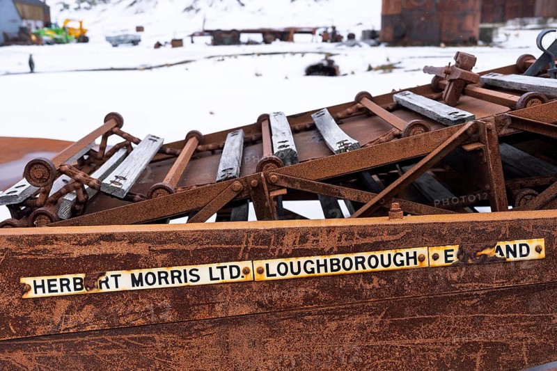 Rusted machine parts with manufacturer's sign Herbert Morris Ltd. Loughborough England, remains of the former whaling station, snow, Grytviken, South Georgia