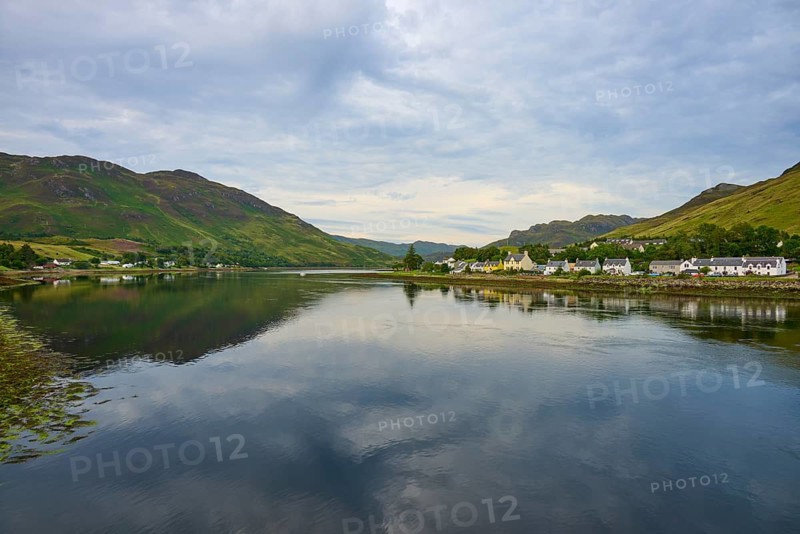 Tranquil seascape with mountains and a small village on the shore under cloudy sky, Dornie, Kyle of Lochalsh, Scotland, United Kingdom, Great Britain