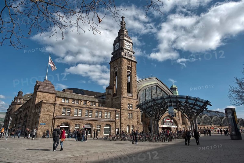 Back side of Hamburger Bahnhof with clock tower, busy forecourt with people under a blue sky, Hamburg, Germany