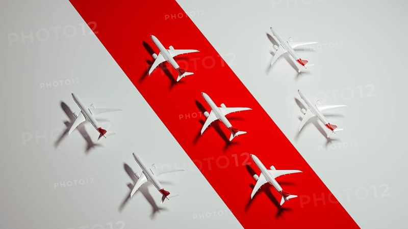 Miniature airplane models are displayed on a striking red surface, highlighting the concept of air travel and vacation planning