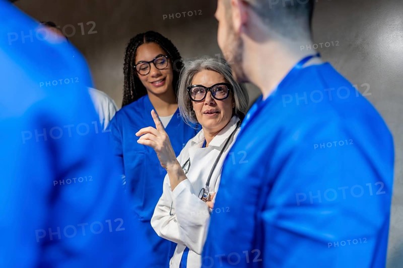 Diverse healthcare professionals, including doctors and nurses, engaging in a focused discussion and collaboration, planning patient care within a clinical environment