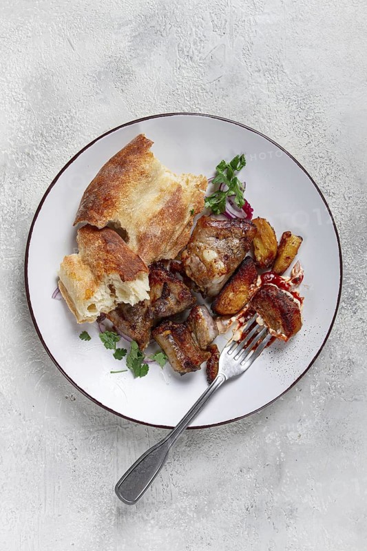A plate with leftover pork kebab, with bread, on a white plate, close-up, there are no people