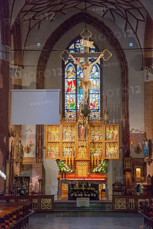 Gothic altar in a church, decorated with a crucifix and stained glass window in the background, St. Jacob's Church, Olsztyn, Allenstein, Warmia-Masuria, Poland