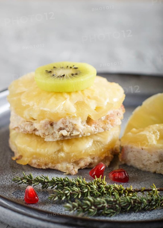 Pieces of baked pork with pineapple, cheese and kiwi on gray plate, side view, close up, selective focus