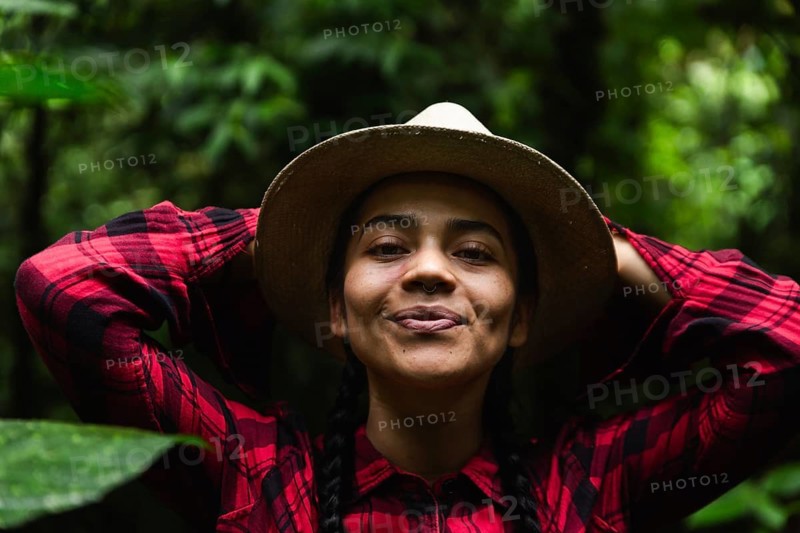 An Ecuadorian woman in a hat and plaid shirt enjoys nature in the lush Choco Andino rainforest of Ecuador, symbolizing adventure and ecotourism