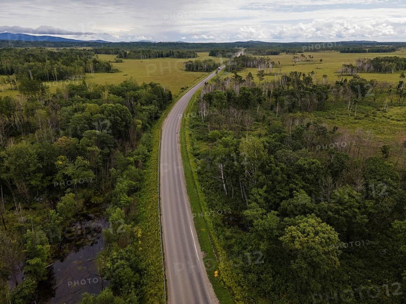 A winding road cuts through lush green fields and forests in Vladivostok, Russia. This peaceful landscape showcases the natural beauty and tranquility of the surrounding area, perfect for outdoor exploration