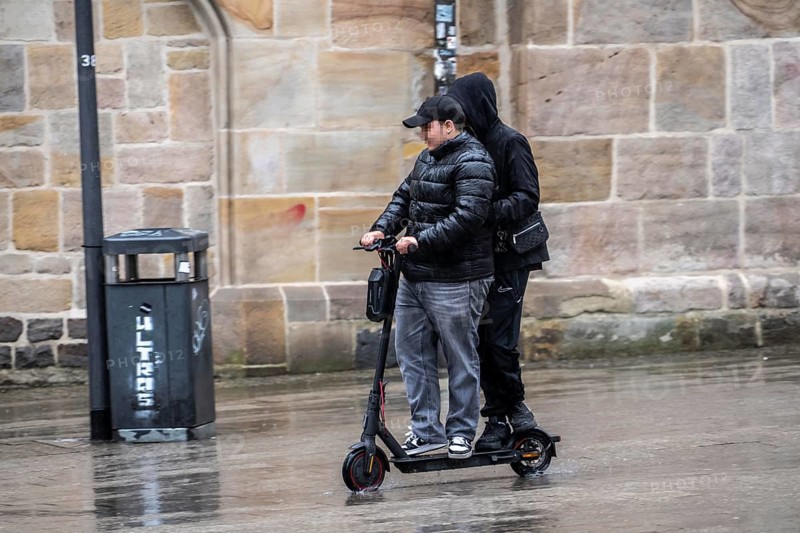City center, shopping street, Kettwiger Straße pedestrian zone in Essen, 2 young men on an e-scooter, electric scooter, rainy weather, North Rhine-Westphalia, Germany